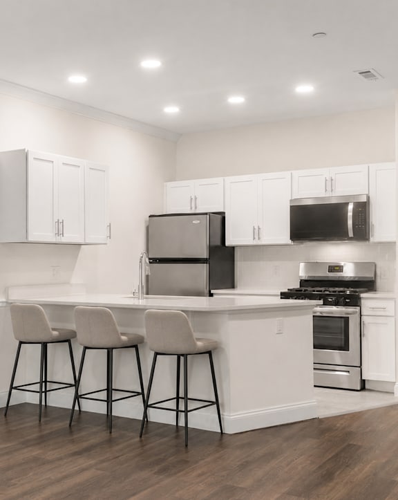 A kitchen with white cabinets and a wooden floor.