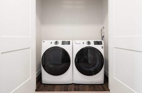 washer and dryer side by side in laundry closet with doors open