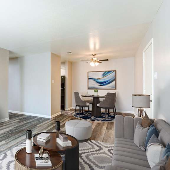 A modern living room with a grey sofa, a wooden coffee table, and a television on a white cabinet.
