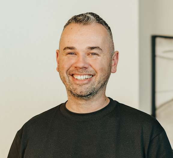 a man in a black shirt smiles at the camera