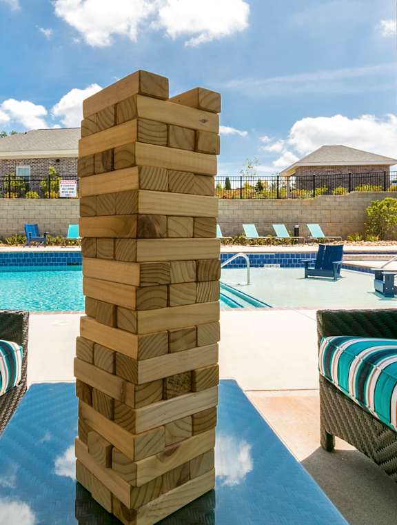 A poolside table with a striped chair and a tall stack of wooden blocks.