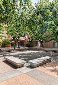 A courtyard with a fountain surrounded by trees and buildings.