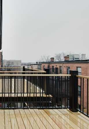 A balcony with a black railing and wooden floor.