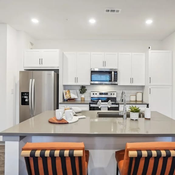A modern kitchen with a refrigerator, microwave, oven, and sink.