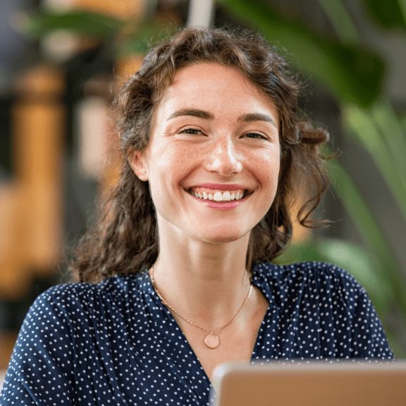 a woman smiling while looking at a laptop computer