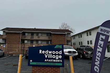 a sign for redwood village apartments in front of a parking lot