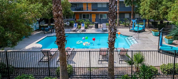 Aerial view of Community pool near Las Vegas strip at Fifteen 50 apartment buildings. Pool is surrounded by patio furniture and palm trees