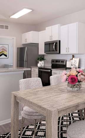 A kitchen with a table and chairs in the foreground and a fridge, microwave, and other appliances in the background.