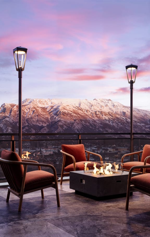 a view of the mountains from a terrace with chairs and a fireplace