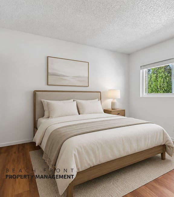 A bedroom with a large bed and a window overlooking a tree-filled area.