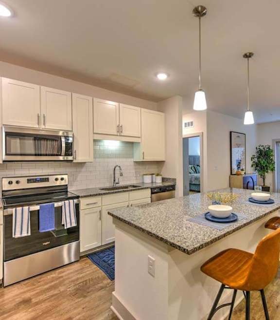 A kitchen with a granite countertop and a dining area with chairs.