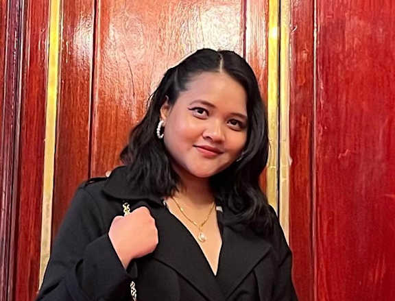 A woman in a black coat holding a pink purse.