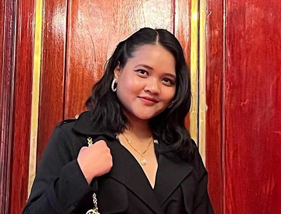 A woman in a black coat holding a pink purse.