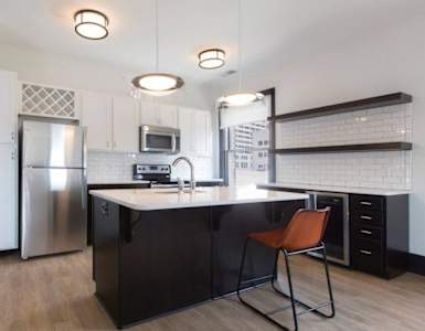 A modern kitchen with a black countertop and a stainless steel refrigerator.