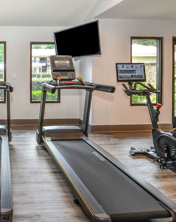 A spacious gym with treadmills, elliptical machines, and a fan.