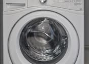 Thumbnail 16 of 17 - A white door is open to reveal a laundry room with a washer and dryer stacked on top of each other.