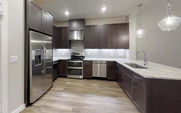 A modern kitchen with dark brown cabinets and stainless steel appliances.