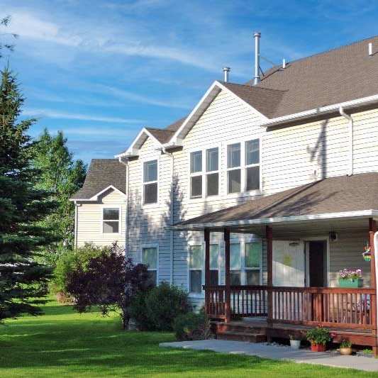 A house with a brown roof and a porch with a flag on it.