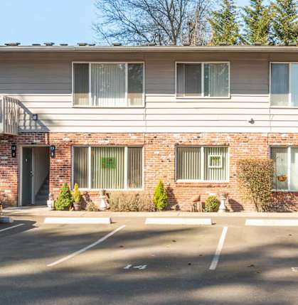 A parking lot in front of a two-story apartment building.