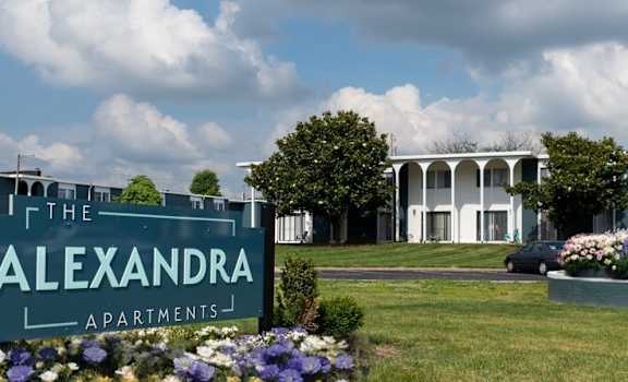 A sign for The Alexandra Apartments is in front of a building.