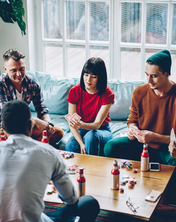 a group of people sitting around a living room playing a board game