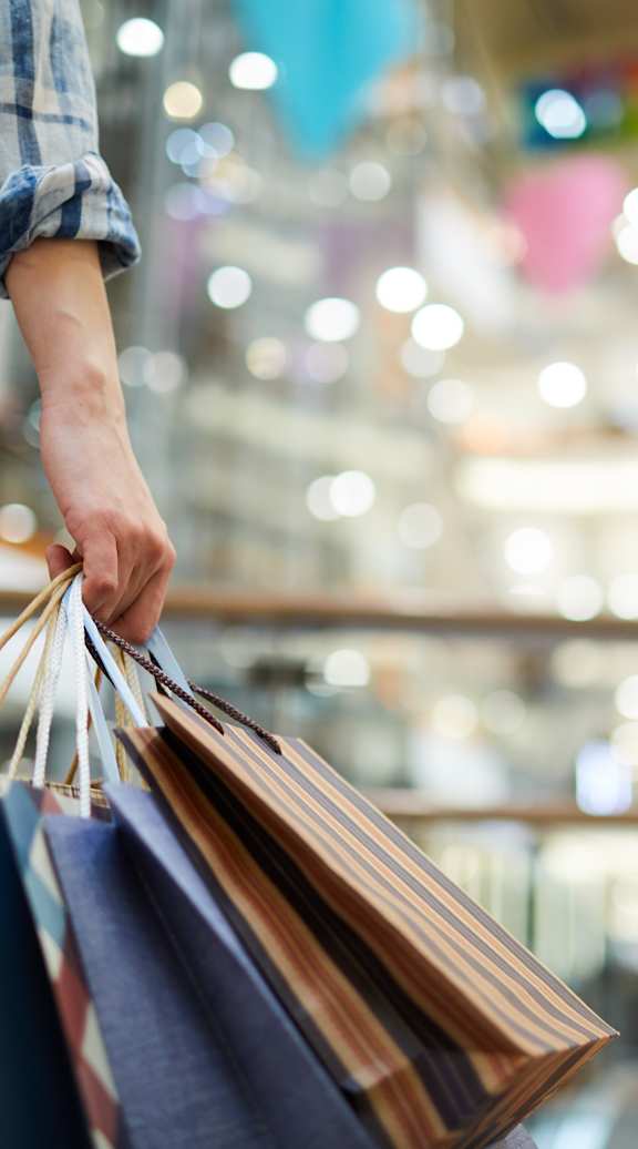 A person is holding shopping bags in a mall.