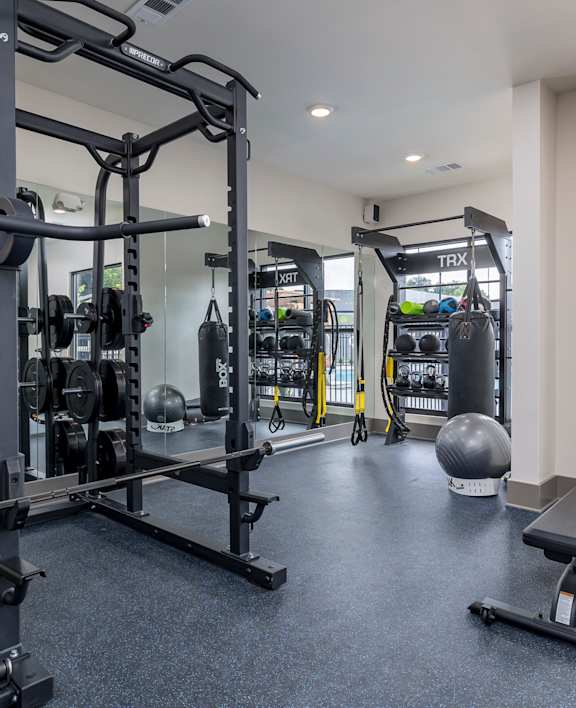 A gym with a variety of equipment including a squat rack, bench, and weights.