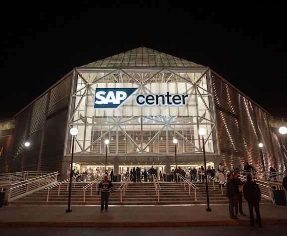 A group of people are standing in front of a building with the words SAP Center on it.