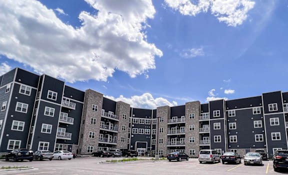 an apartment building in a parking lot under a cloudy sky