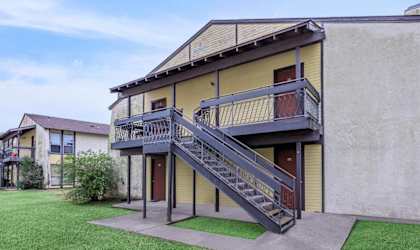 A yellow house with a black staircase leading to the second floor.