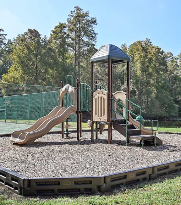 A playground with a slide and a wooden swing set.