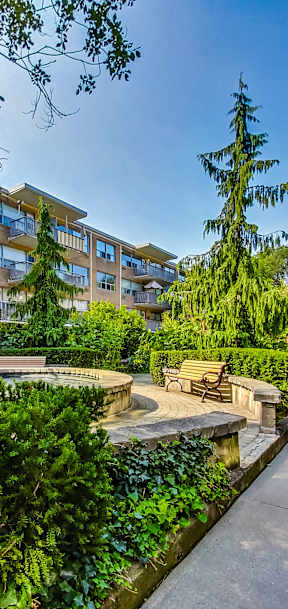 a path between two apartment buildings with green grass and trees