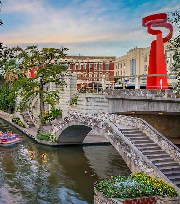 A river runs through a city with a boat carrying people on it.