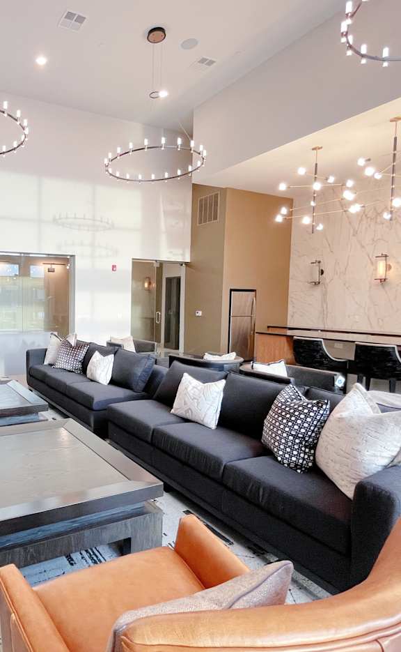 A modern living room with a black couch and orange chairs.