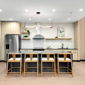 A kitchen with a black refrigerator and wooden bar stools.