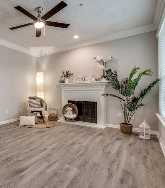 A living room with a fireplace and a ceiling fan. at Montecito Apartments, Texas