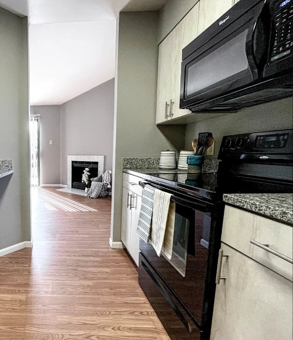A kitchen with wooden floors and black appliances.