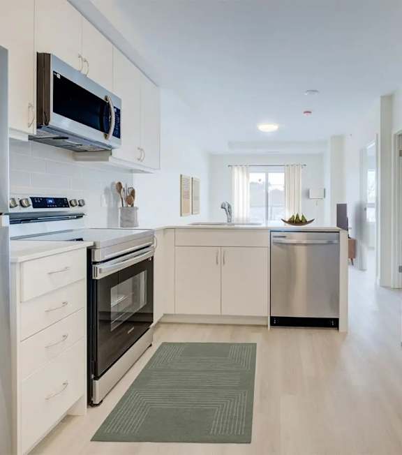 A modern kitchen with white cabinets and stainless steel appliances.at Sylk Towers, Kitchener Ontario