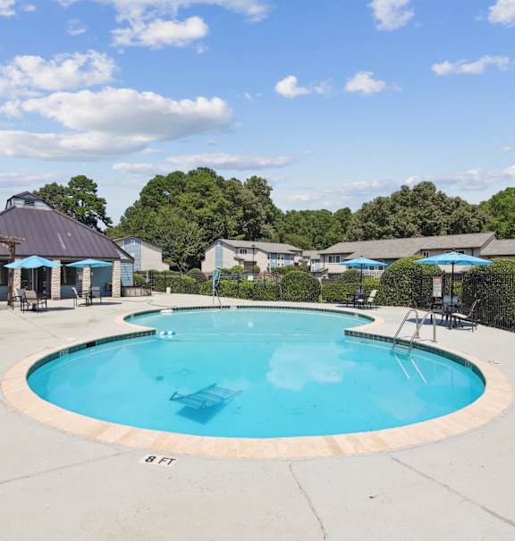 A large outdoor swimming pool surrounded by a fence and trees.