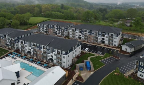 an aerial view of an apartment complex with a pool and mountains in the background