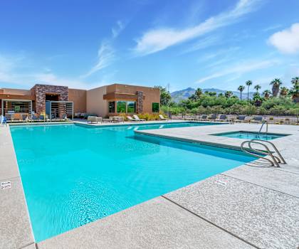 A large swimming pool with a diving board and a building in the background.