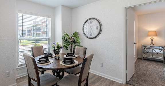 a dining room with a table and chairs and a clock on the wall