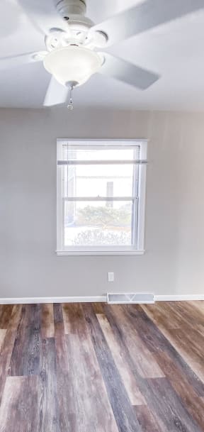 an empty living room with wood floors and a ceiling fan