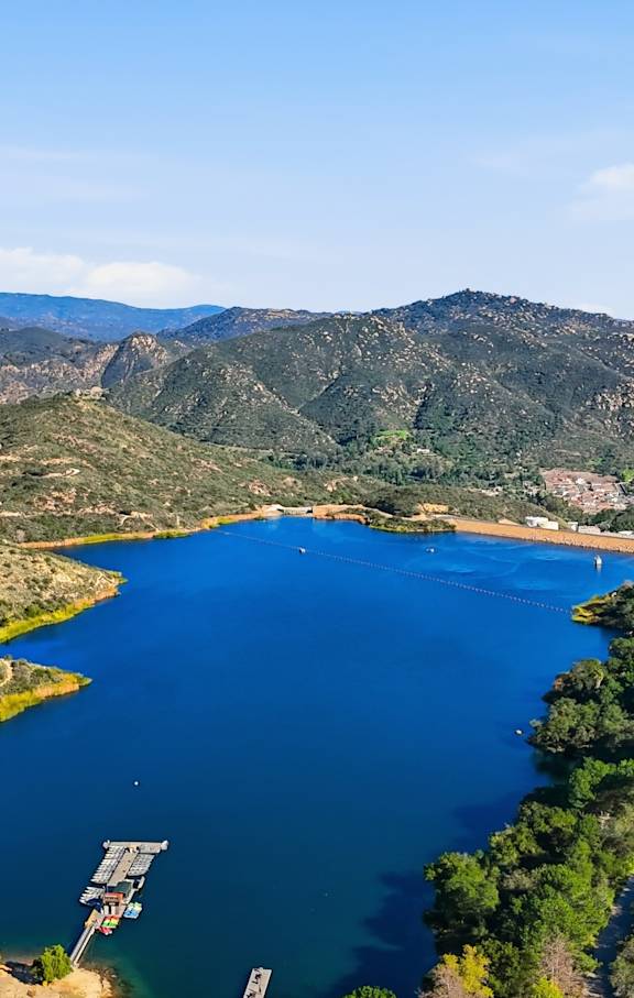 A large body of water surrounded by greenery and mountains.
