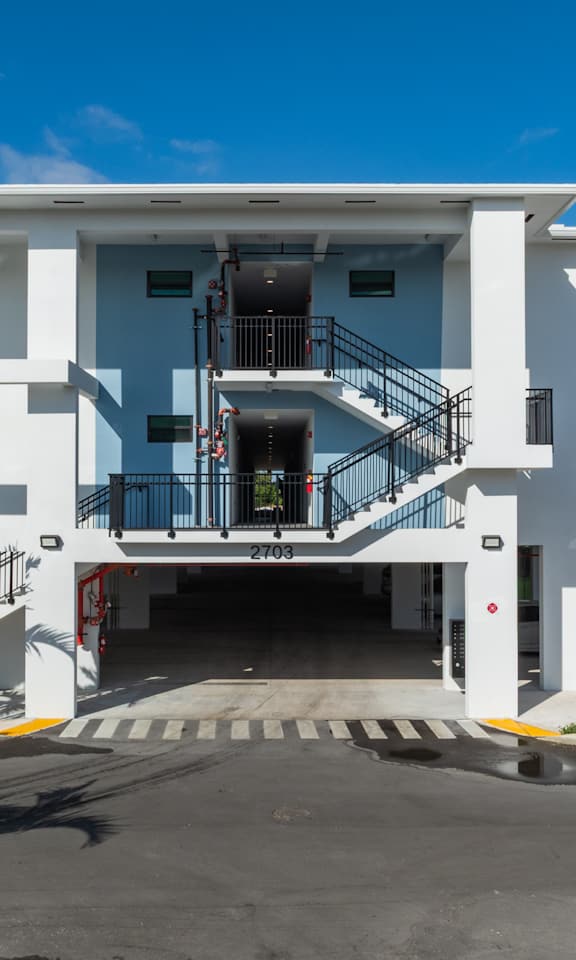A white two-story building with a black railing on the balcony.