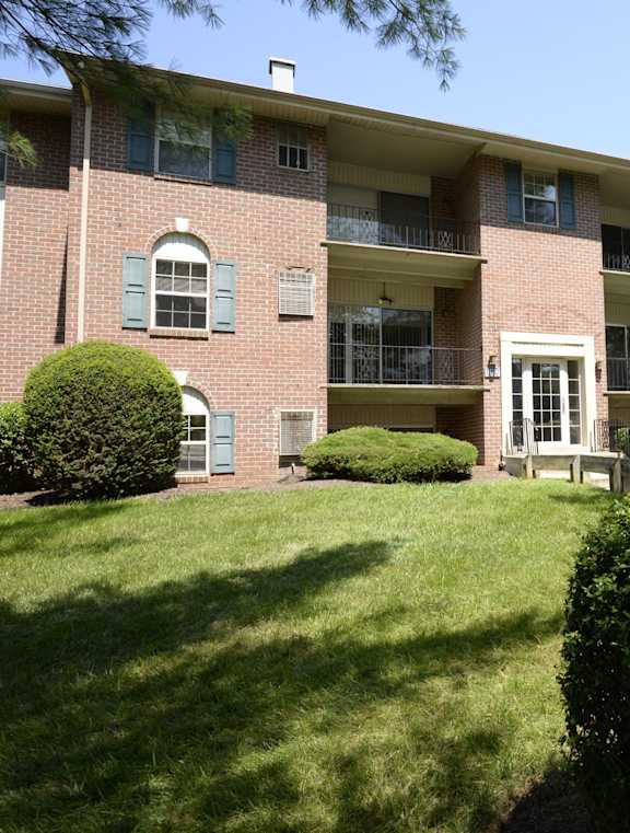 A red brick apartment building with a green lawn in front.