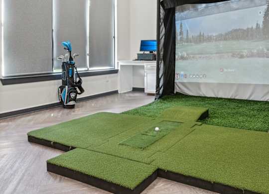 A room with a golf simulator and a golf cart.