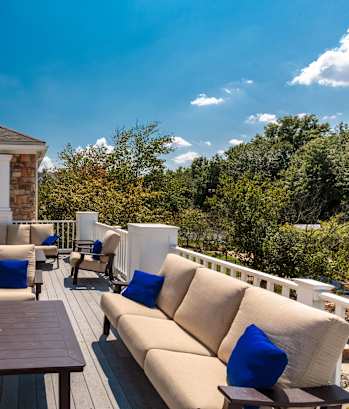 A wooden deck with a table and chairs is surrounded by a stone wall.