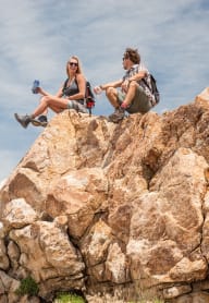 a couple of people sitting on top of a rock