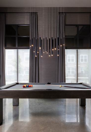 A pool table in a room with a light hanging from the ceiling.